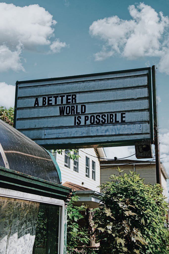 Inspirational message on a signboard against a cloudy sky, encouraging positive change.